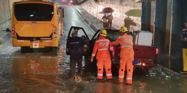 Micro-ônibus com 12 pessoas e carro ficam imobilizados em alagamento na avenida Governador Valadares em Arcos